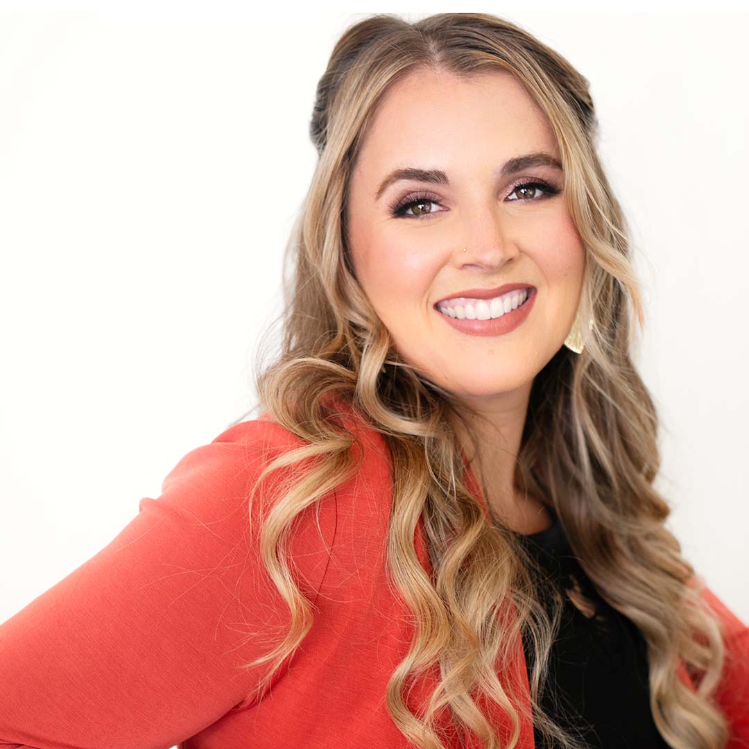 Headshot of Natasha Clawson wearing a bright orange blazer